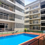 Pool area at Crown of the Ridge with beautifully paved walkways, glass and metal balustrade, surrounded by apartments with balconies and manicured grass