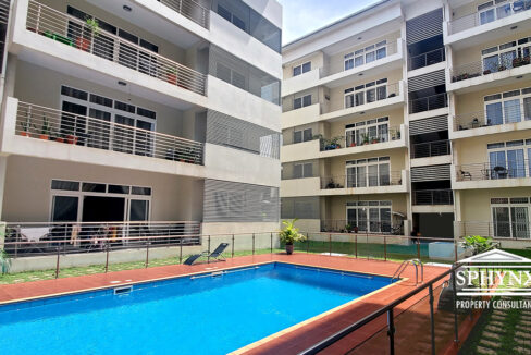 Pool area at Crown of the Ridge with beautifully paved walkways, glass and metal balustrade, surrounded by apartments with balconies and manicured grass