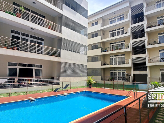 Pool area at Crown of the Ridge with beautifully paved walkways, glass and metal balustrade, surrounded by apartments with balconies and manicured grass